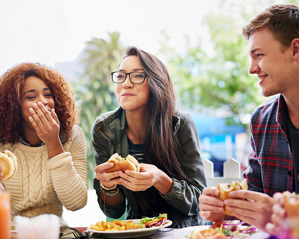 Three friends at a restaurant eating food; Therapy for disordered eating in Bellevue, WA