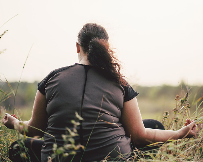 Young woman doing yoga in a field, celebrating body image after therapy in Bellevue