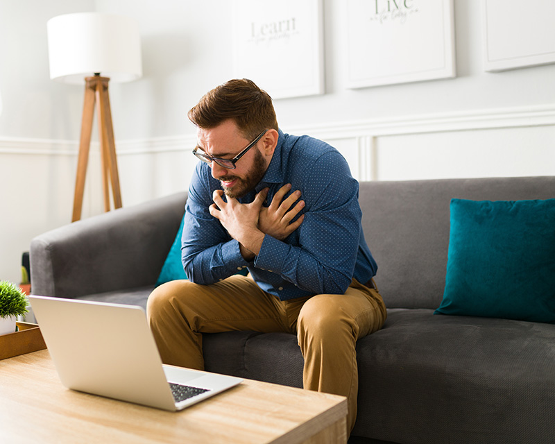 Young man on a couch with a laptop doing an EMDR intensive with Sarah Dochow